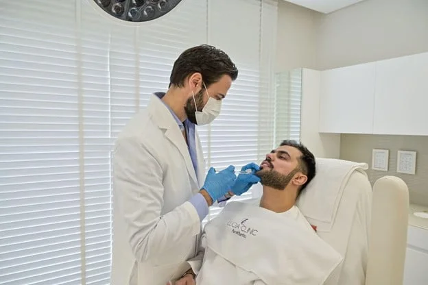 The doctor is enhancing the patient’s chin with Dermal fillers