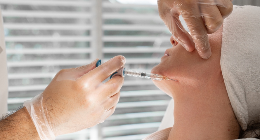 A side view of a woman receiving dermal filler injections in the lower face.