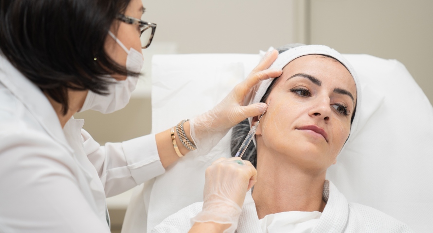 A dermatologist performing dermal filler treatment on a smiling patient.