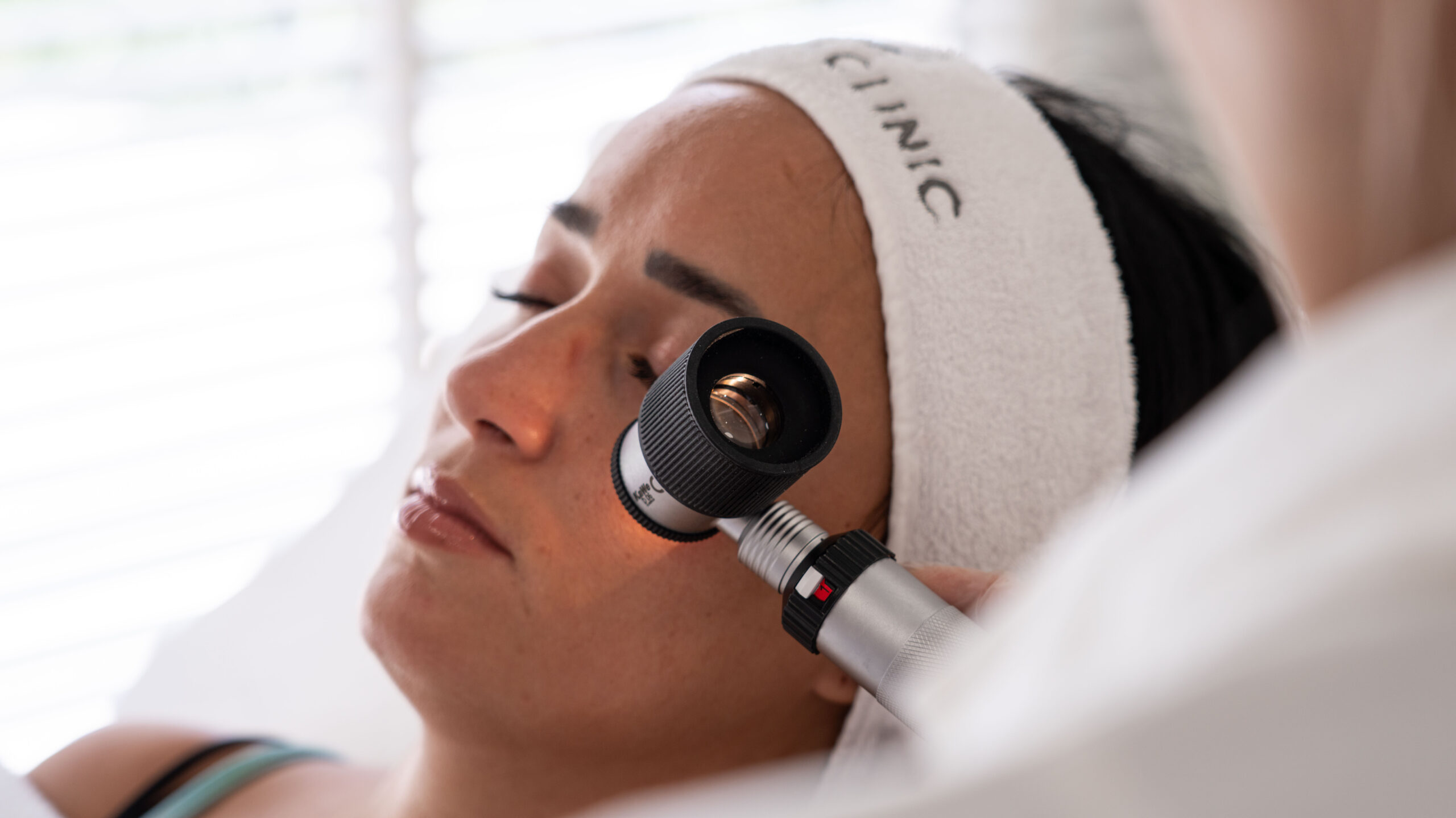 A dermatologist examining a patient's skin with a dermatoscope at Lucia Clinic.