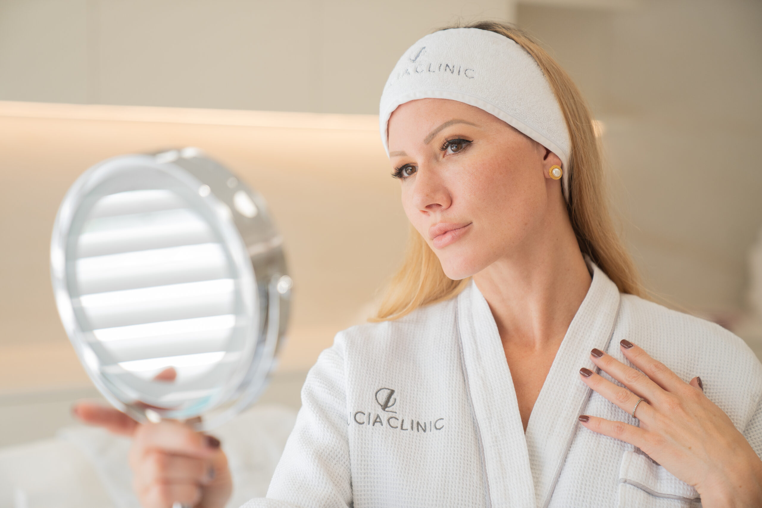 A woman looking at a mirror after botox treatment at Lucia Clinic