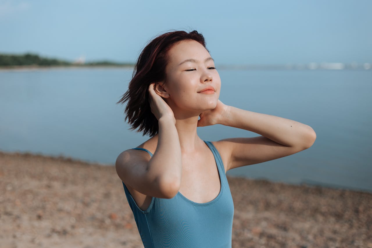 A young woman at the beach showing her keratosis pilaris free elbows