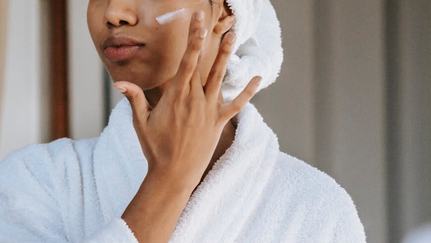 A woman putting on cosmetic cream