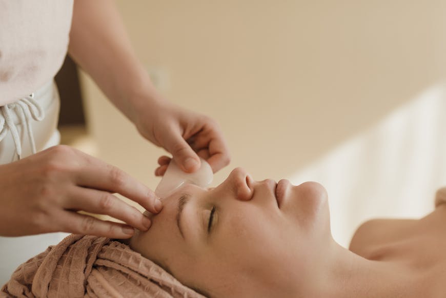 Cosmetologist using a gua sha on a patient's face.