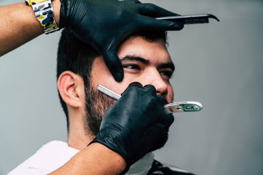 A man getting his bear shaved