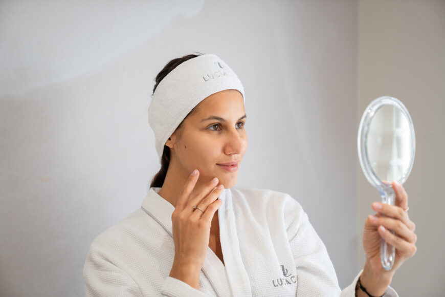 A woman looking at the mirror after collagen stimulation at Lucia Clinic
