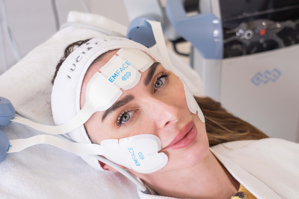 A person lies on a treatment table, with medical equipment and wires attached to their head, and a towel covering their shoulders.