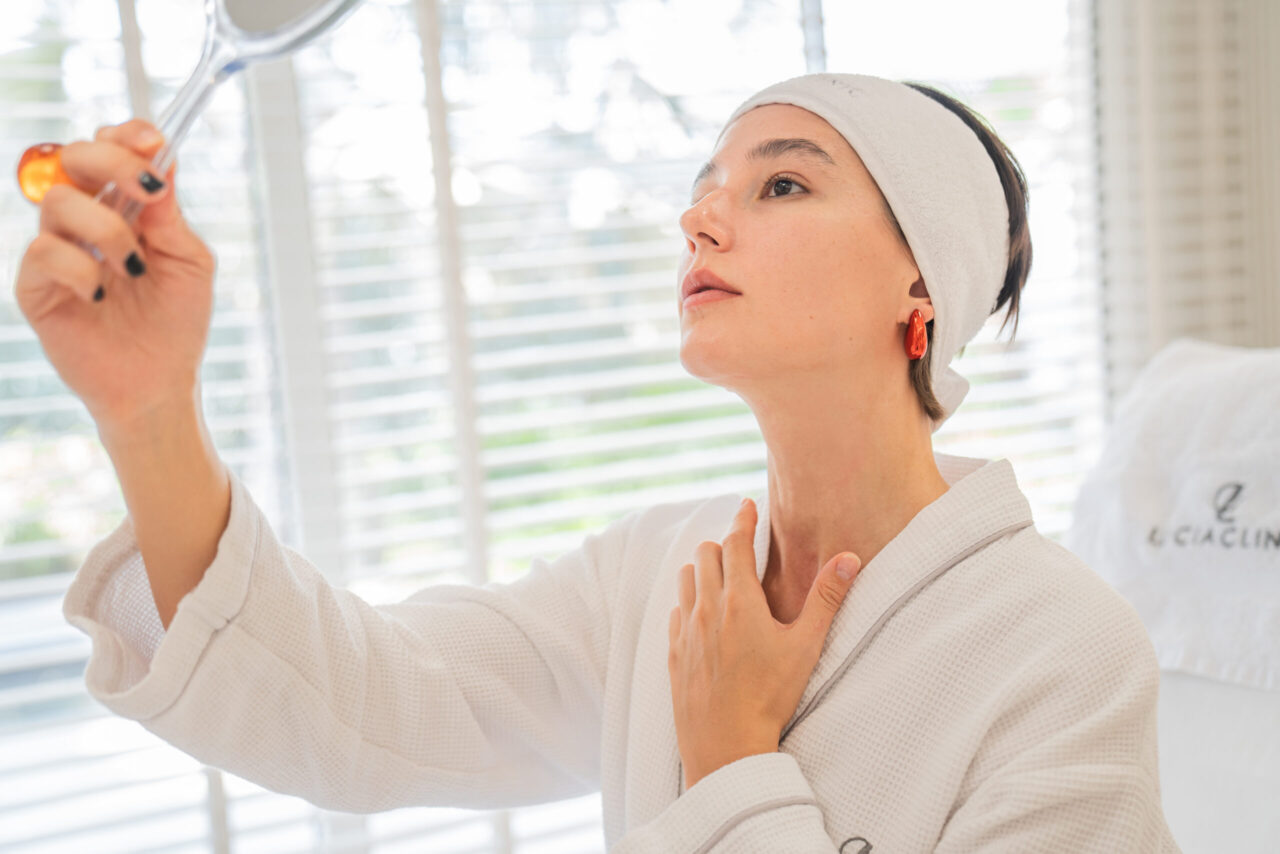 A woman looking at a mirror after doing top dermatology treatments in Dubai for common skin issues